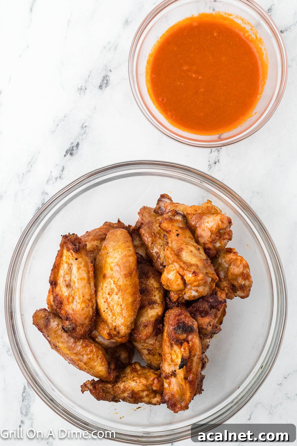 Cooked Chicken Wings in a bowl with a small bowl of buffalo sauce on the side