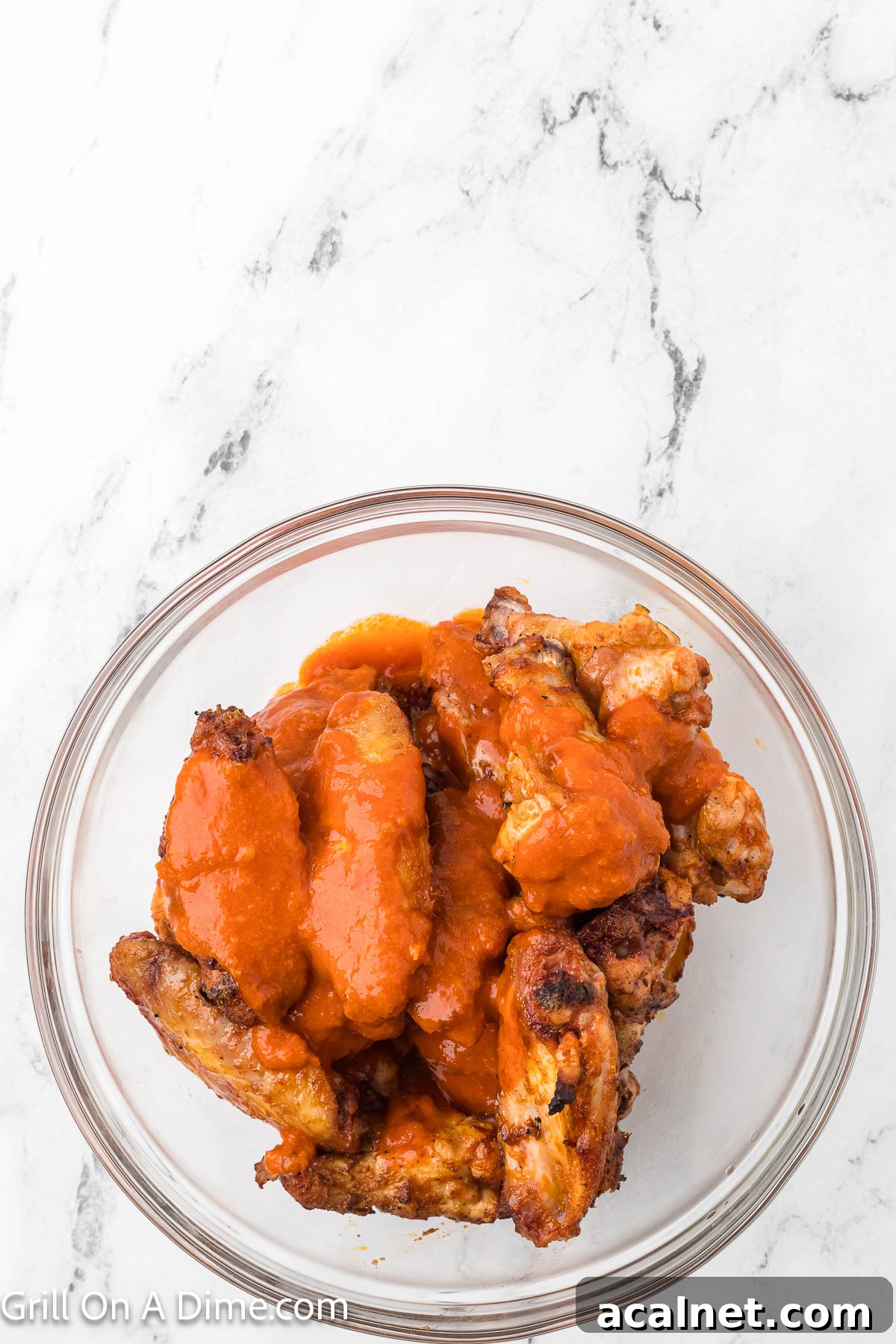 Chicken Wings in a bowl topped with buffalo sauce