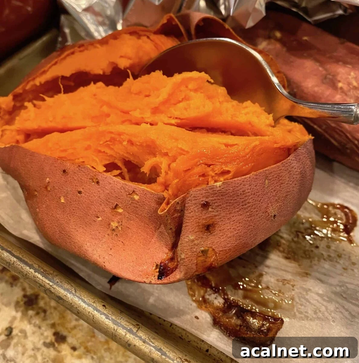 Baked sweet potato sliced open with a spoon scooping out the filling
